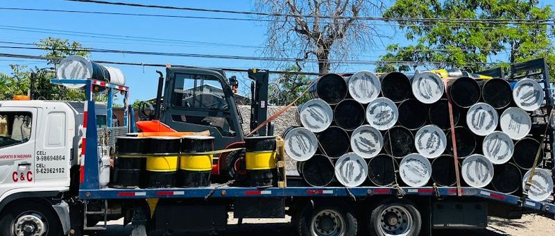 Camión rampla cargado con ductos metálicos y tambores industriales
